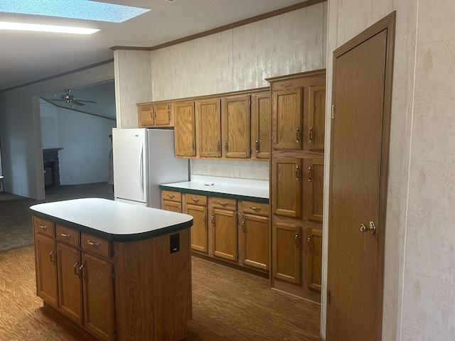 2503 W Hubbard Lake Trl, Hubbard Lake, MI 49747 - kitchen with freestanding refrigerator, brown cabinets, dark wood-style flooring, ornamental molding, and ceiling fan