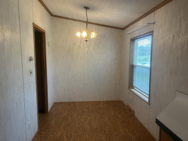 2503 W Hubbard Lake Trl, Hubbard Lake, MI 49747 - unfurnished dining area featuring ornamental molding, wood finished floors, a chandelier, and a textured ceiling