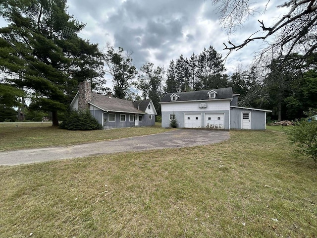 302 S Vine St, Mio, MI 48647 - view of green lawn featuring asphalt driveway, an outbuilding, and a garage