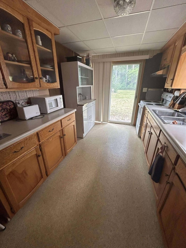 302 S Vine St, Mio, MI 48647 - kitchen with white appliances, a paneled ceiling, glass insert cabinets, brown cabinetry, and under cabinet range hood