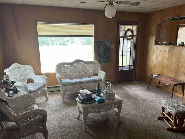 302 S Vine St, Mio, MI 48647 - living area with carpet flooring, wood walls, ceiling fan, plenty of natural light, and a drop ceiling