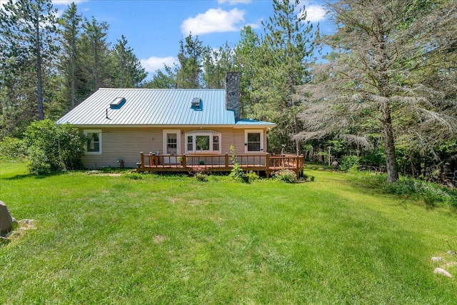 2951 N Palmer Rd, Onaway, MI 49765 - back of property featuring a metal roof, a deck, a chimney, a yard, and a standing seam roof