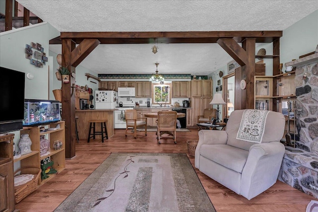 2951 N Palmer Rd, Onaway, MI 49765 - living area with a textured ceiling, light wood finished floors, and beamed ceiling
