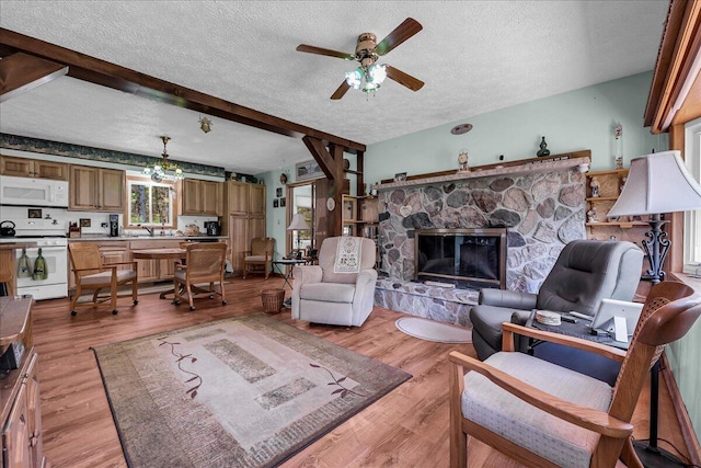 2951 N Palmer Rd, Onaway, MI 49765 - living room with a textured ceiling, ceiling fan, a fireplace, light wood-style flooring, and beam ceiling