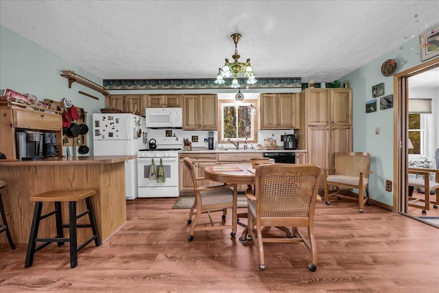 2951 N Palmer Rd, Onaway, MI 49765 - kitchen with white appliances, a textured ceiling, light wood finished floors, and a kitchen bar