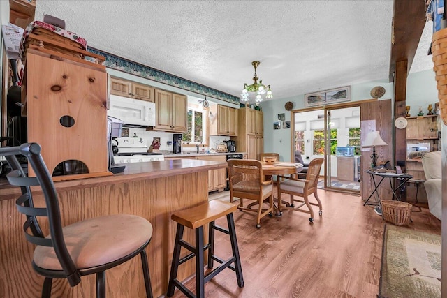 2951 N Palmer Rd, Onaway, MI 49765 - kitchen with a textured ceiling, white appliances, light wood-type flooring, a kitchen breakfast bar, and a chandelier