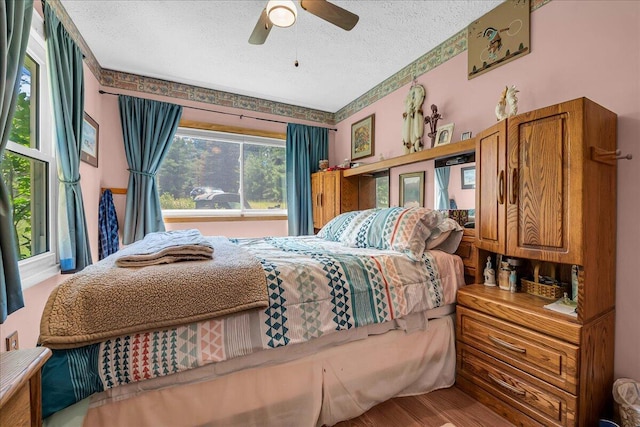 2951 N Palmer Rd, Onaway, MI 49765 - bedroom featuring a textured ceiling, wood finished floors, and a ceiling fan