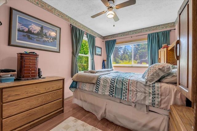 2951 N Palmer Rd, Onaway, MI 49765 - bedroom featuring wood finished floors, a textured ceiling, and a ceiling fan