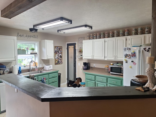 13631 Tolan Rd, Ossineke, MI 49766 - kitchen featuring freestanding refrigerator, white cabinets, a textured ceiling, stainless steel microwave, and a peninsula