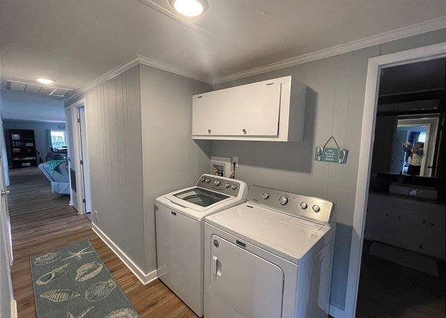 washroom with washer and dryer, crown molding, dark wood-type flooring, and cabinets