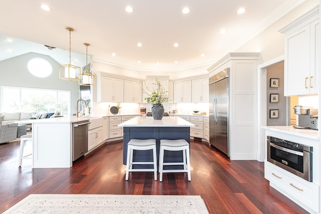 kitchen featuring white cabinetry, stainless steel appliances, dark hardwood / wood-style flooring, kitchen peninsula, and a breakfast bar