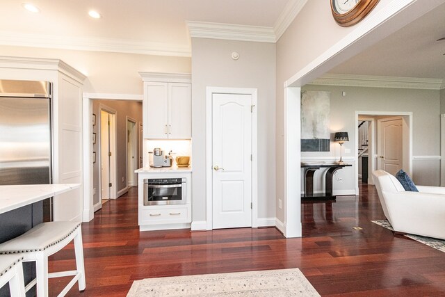 kitchen featuring white cabinets, dark hardwood / wood-style flooring, stainless steel appliances, and crown molding