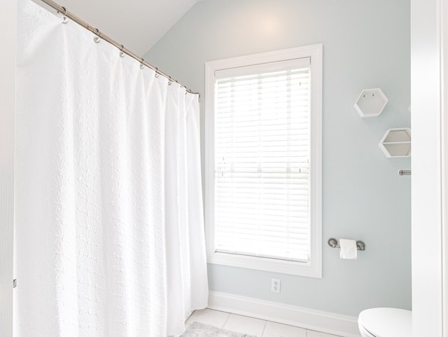 bathroom with toilet, tile patterned floors, and lofted ceiling