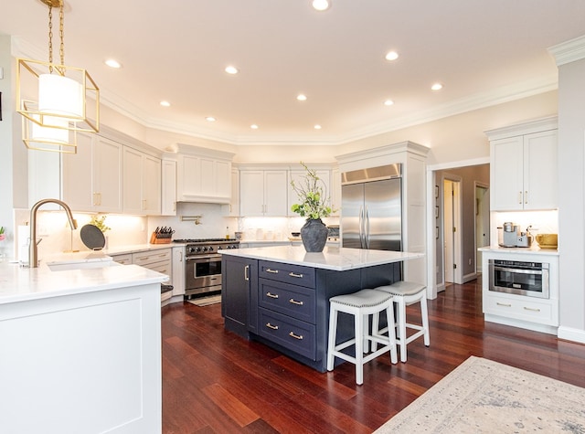 kitchen with white cabinets, a breakfast bar, high end appliances, and sink