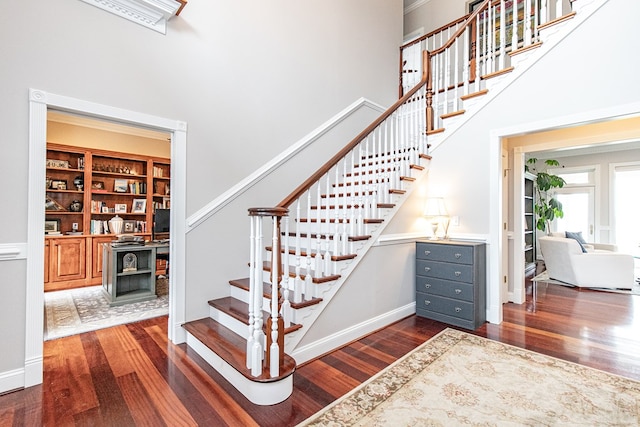 stairs featuring hardwood / wood-style floors, built in shelves, and a high ceiling