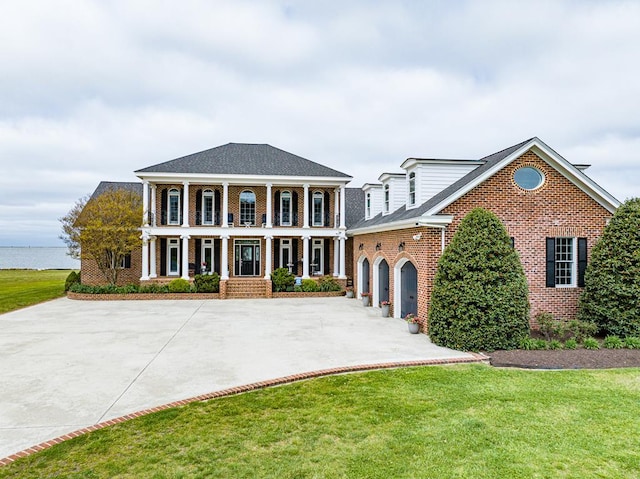 view of front facade with a water view, a porch, a garage, and a front yard