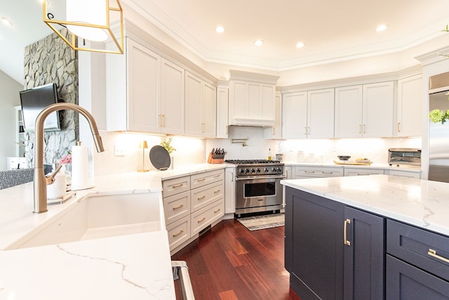 kitchen featuring dark hardwood / wood-style flooring, light stone counters, sink, pendant lighting, and stainless steel stove