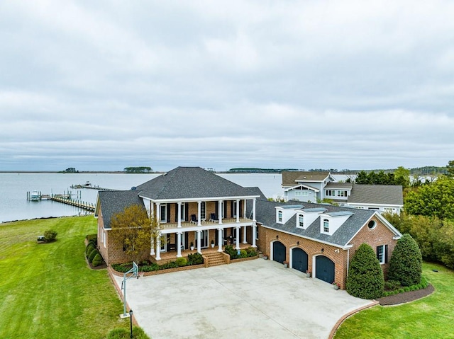 view of front of house with covered porch, a water view, a front lawn, and a balcony