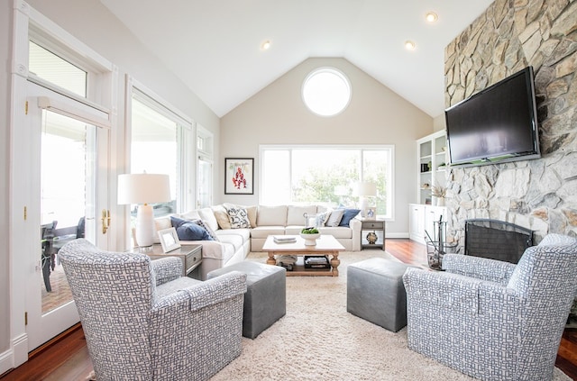 living room with a stone fireplace, a healthy amount of sunlight, and wood-type flooring