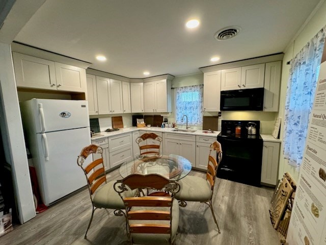 kitchen with white cabinets, light wood-type flooring, sink, and black appliances