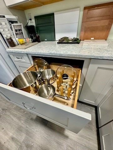 interior details featuring gray cabinets, light stone counters, and light hardwood / wood-style flooring