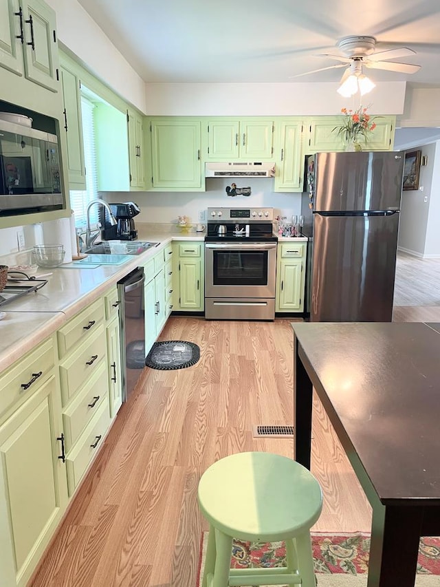 7669 E Side Rd, Chincoteague, VA 23336 - kitchen featuring stainless steel appliances, green cabinets, light wood-style flooring, a ceiling fan, and under cabinet range hood