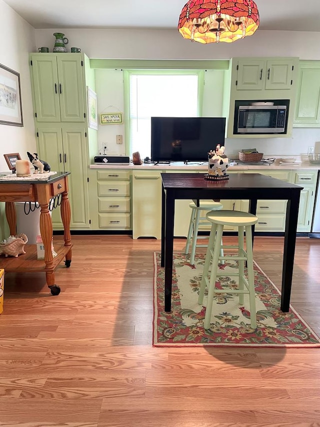 7669 E Side Rd, Chincoteague, VA 23336 - kitchen featuring stainless steel microwave, green cabinets, light wood-type flooring, and fridge