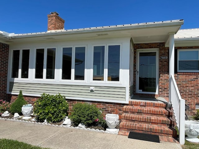 7669 E Side Rd, Chincoteague, VA 23336 - view of exterior entry with a chimney, metal roof, and brick siding