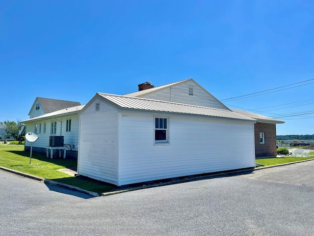7669 E Side Rd, Chincoteague, VA 23336 - view of side of property with a chimney, central air condition unit, and metal roof