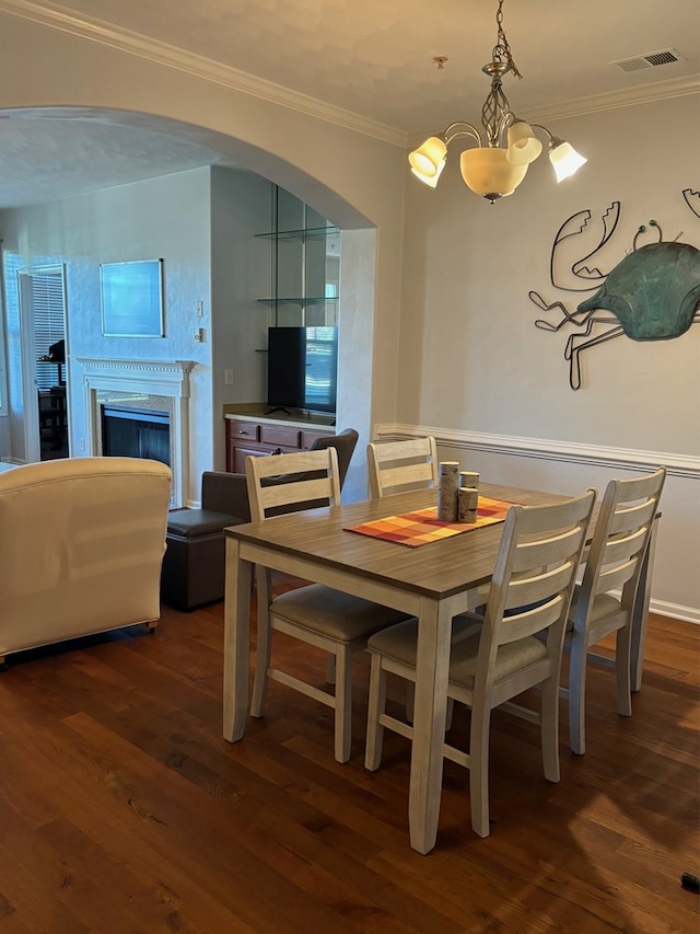 dining room featuring an inviting chandelier, ornamental molding, and dark hardwood / wood-style floors