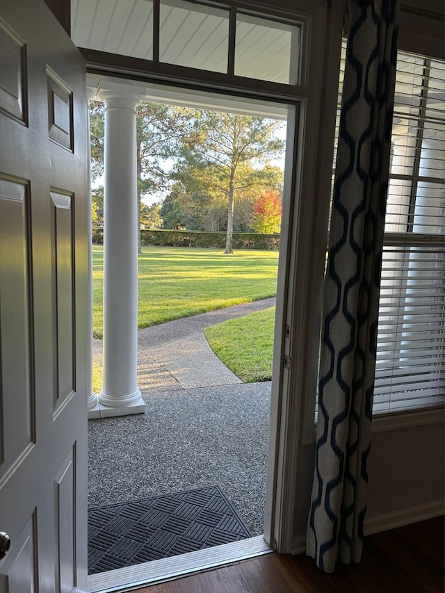 doorway to outside with a wealth of natural light, decorative columns, and dark hardwood / wood-style floors