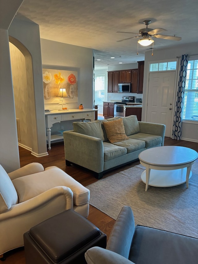 living room featuring dark wood-type flooring and ceiling fan