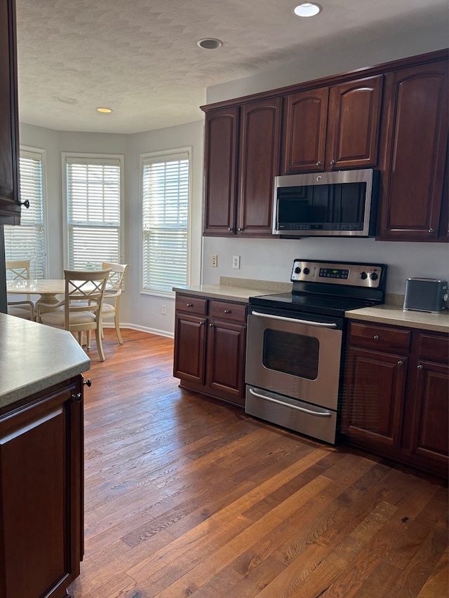 kitchen with appliances with stainless steel finishes and dark hardwood / wood-style flooring