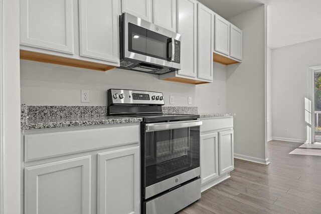 LOT476 Driftwood Dr, Greenbackville, VA 23356 - kitchen featuring appliances with stainless steel finishes, baseboards, light wood finished floors, light stone countertops, and white cabinets