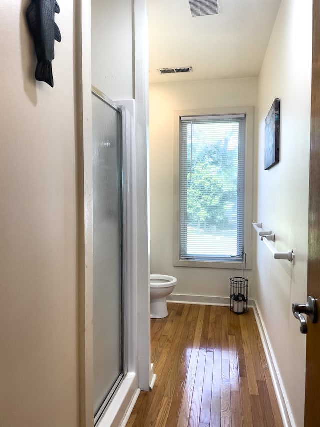 bathroom featuring hardwood / wood-style flooring, toilet, and walk in shower