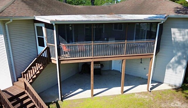 rear view of house featuring a wooden deck, a sunroom, and a patio