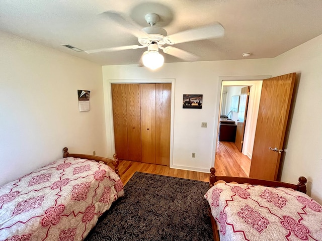 bedroom with light wood-type flooring, ceiling fan, and a closet