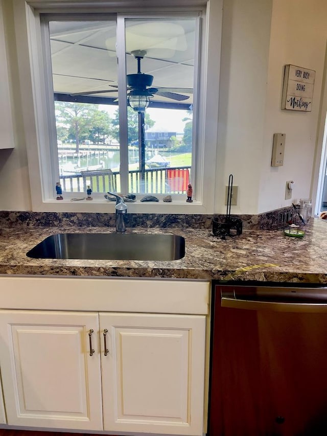 kitchen with dark stone countertops, sink, stainless steel dishwasher, and white cabinets