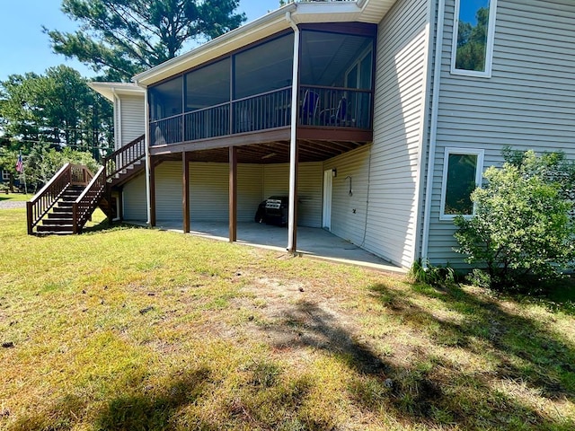 back of house with a sunroom, a patio area, and a lawn