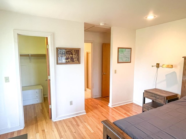 bedroom with a walk in closet, a closet, and light wood-type flooring