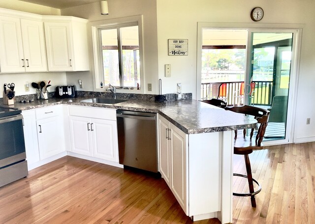 kitchen with white cabinetry, appliances with stainless steel finishes, kitchen peninsula, and sink