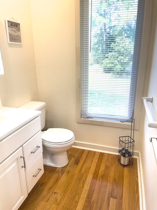 bathroom with a healthy amount of sunlight, vanity, toilet, and hardwood / wood-style floors