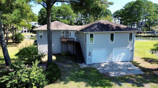 back of property with a deck with water view, a garage, and a lawn