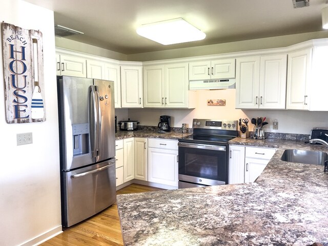 kitchen featuring appliances with stainless steel finishes, sink, white cabinets, and light hardwood / wood-style floors