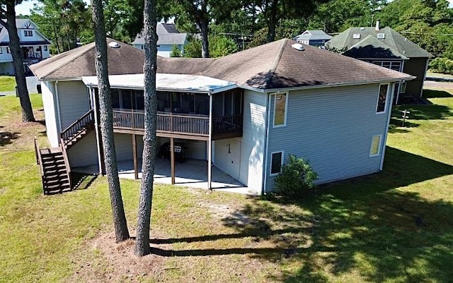 back of property with a yard, a patio area, and a sunroom