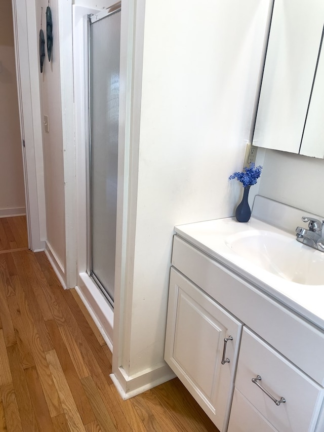 bathroom featuring hardwood / wood-style flooring, vanity, and walk in shower