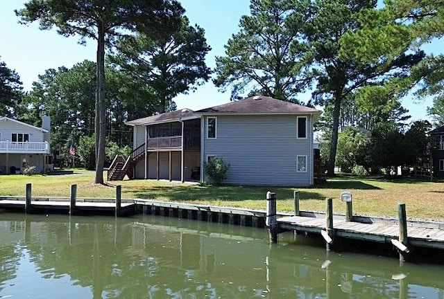 back of property featuring a lawn, a sunroom, and a water view