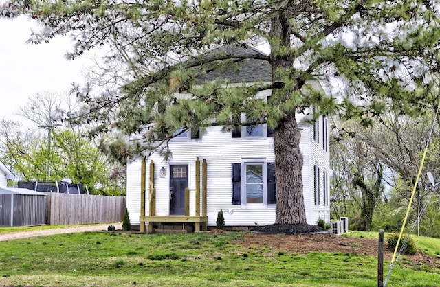 view of front of house featuring cooling unit, a front lawn, and fence