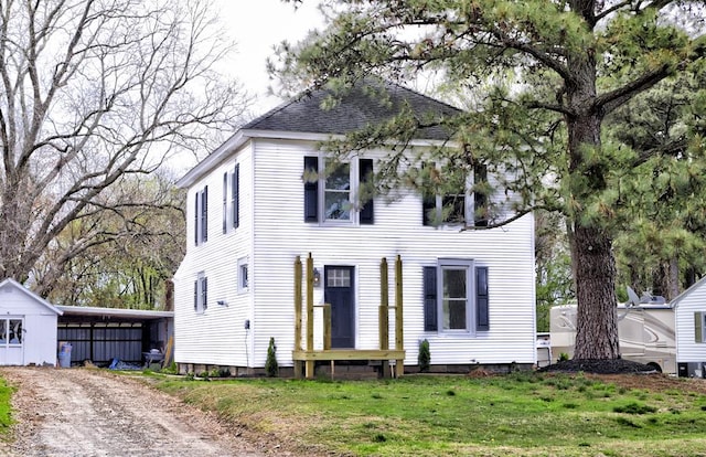 view of front of property featuring a carport, a front yard, driveway, and roof with shingles