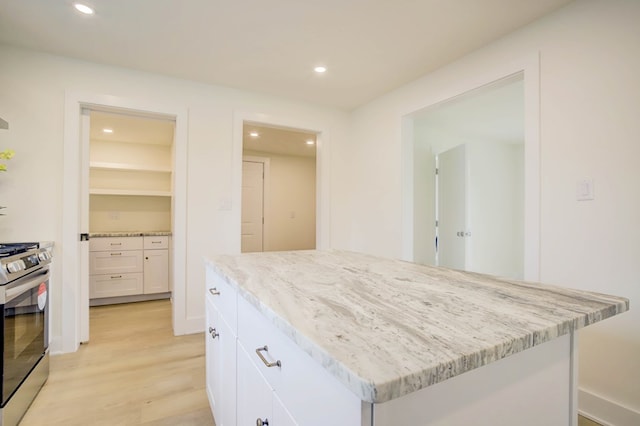 kitchen featuring stainless steel gas range, light stone countertops, light wood finished floors, and recessed lighting